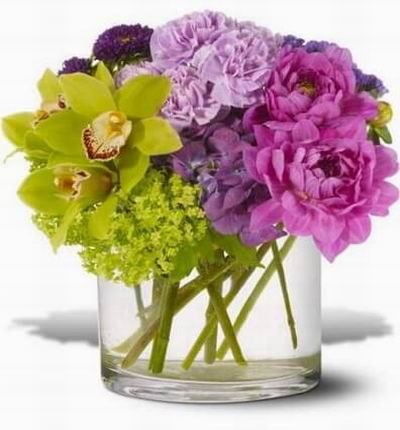Green orchids and purple dahlias mingle with lavender and chartreuse blooms. Green cymbidium orchids and viburnum.