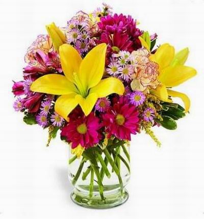 Yellow Asiatic lilies and purple daisy poms are sprinkled with mini carnations and lavender monte casino and in glass vase