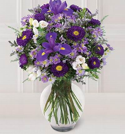 Purple iris are surrounded by lavender freesia, purple asters and greenery.