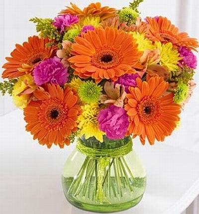 Brightly colored bouquet of orange Gerbera daisies, yellow poms, hot pink mini carnations, and vivid green button poms